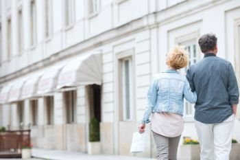 Rear view of middle-aged couple walking by building