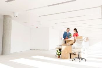 Business people discussing while standing by cardboard boxes in new office