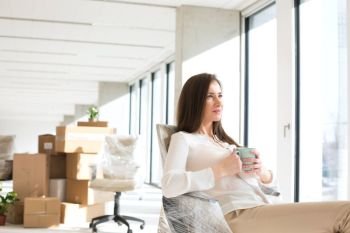 Thoughtful young businesswoman having coffee in new office