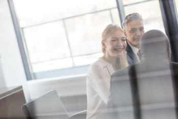 Smiling young businesswoman with male colleagues in meeting room