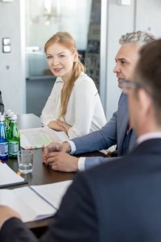 Portrait of young businesswoman sitting with male colleagues in conference room