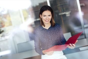 Portrait of confident young businesswoman holding file in office
