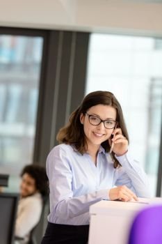 Portrait of smiling young businesswoman talking on mobile phone at office