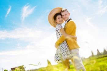 Side view portrait of romantic couple embracing on field against sky
