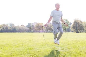 Determined senior man working out with skipping rope in park