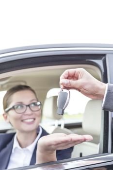 Cropped hand giving car key to businesswoman in vehicle