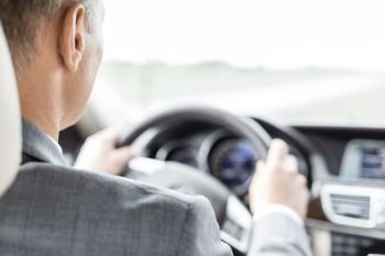 Business executive in suit driving car