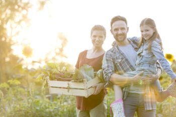 Portrait of smiling family with vegetables in crate at farm