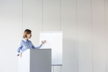 Businesswoman giving presentation at podium in office