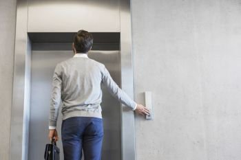 Rear view of businessman waiting for elevator at office