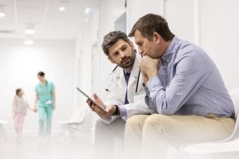 Doctor discussing over digital tablet with mature patient at hospital