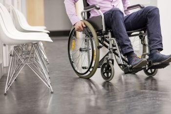 Low section of man sitting on wheelchair at hospital corridor