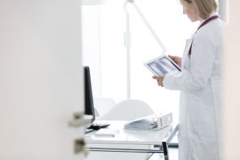 Doctor examining x-ray on digital tablet while standing at desk in hospital
