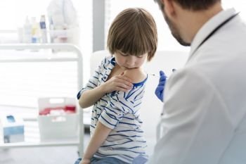Mid adult doctor injecting boy in hospital