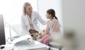 Smiling doctor talking to girl patient at hospital