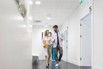 Colleagues discussing while talking in corridor at hospital