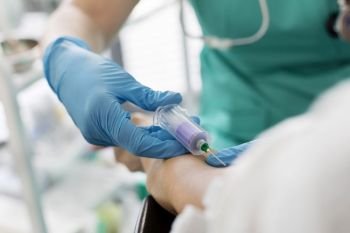 Nurse wearing gloves while injecting patient at hospital
