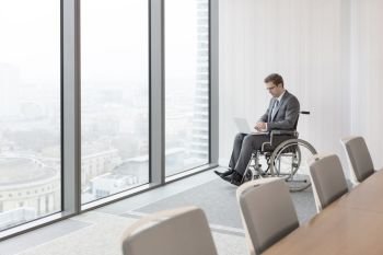 Disabled businessman using laptop in boardroom at modern office