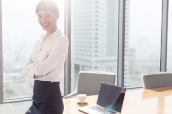 Portrait of smiling businesswoman sitting on table in boardroom at office