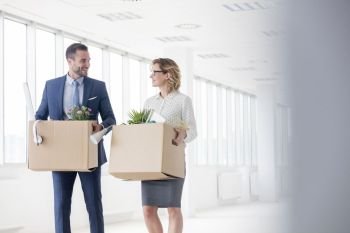 Smiling business colleagues carrying cardboard boxes at new office