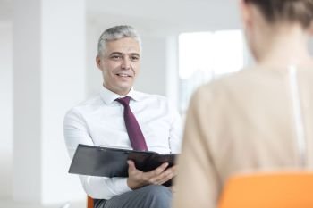 Smiling mature businessman discussing with young businesswoman at new office