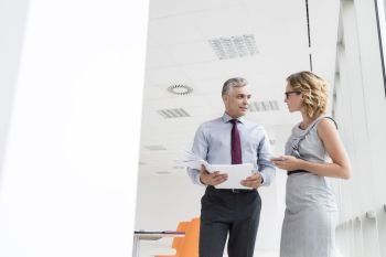 Mature businessman discussing with businesswoman standing at new office