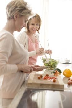 Smiling mature friends preparing meal in kitchen