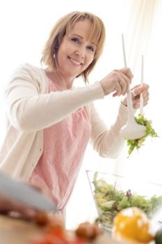 Portrait of smiling woman preparing salad bowl at kitchen