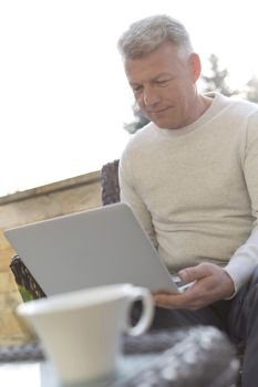 Mature man using laptop while sitting at patio