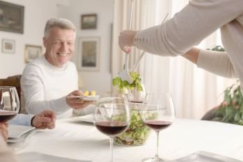 Woman serving salad to smiling man at dining table
