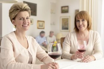 Portrait of smiling mature women sitting with wineglasses at dining table