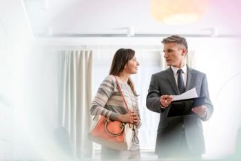Confident mature male realtor discussing contract with female buyer in apartment