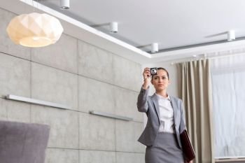 Confident young female realtor photographing while standing in apartment