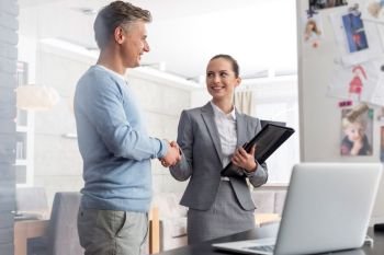 Smiling young saleswoman shaking hands with mature man in apartment