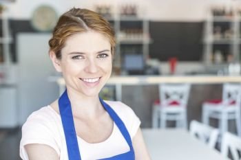 Closeup portrait of smiling young waitress standing at restaurant