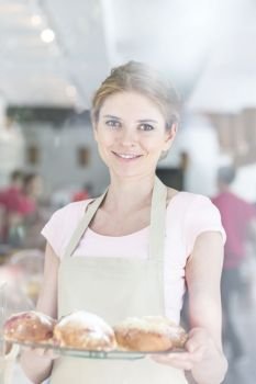 Portrait of smiling beautiful young waitress serving fresh bread at restaurant