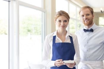 Portrait of confident young staff standing at restaurant