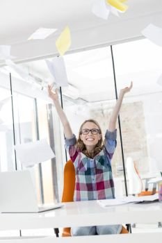 Creative businesswoman throwing documents while celebrating victory in office