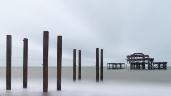 Landscape image of derelict Victorian West Pier at Brighton in West Sussex with moody evening sky