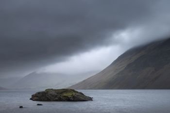 Beautiful long exposure landscape image of Wast Water in UK Lake District during moody Spring evening