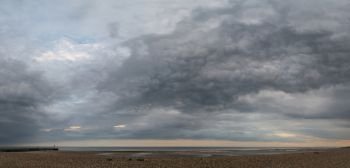 Beautiful panorama landscape image of beach at low tide with moody storm clouds gathering overhead