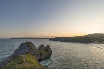Beautiful Summer evening sunset beach landscape image at Three Cliffs Bay in South Wales 