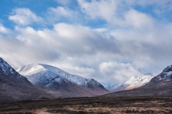 Stunning beautiful Winter landscape image of Lost Valley in Scotland with snowcapped Buachaile Etive Baeg sand distant mountain range with dramatic sky