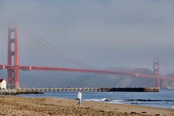 Woman walking on beach near Golden Gate Bridge, San Francisco, California, USA
