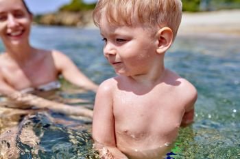 Two year old toddler boy on beach with mother 
