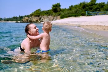 Two year old toddler boy on beach with mother 