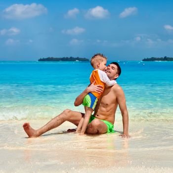 Three year old toddler boy on beach kissing father. Summer family vacation at Maldives.
