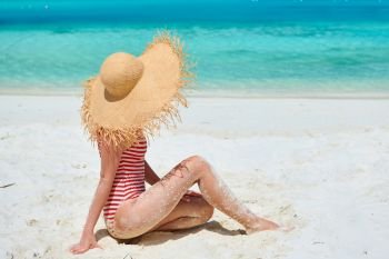 Woman in one-piece swimsuit at tropical beach with white sand. Summer vacation at Maldives.