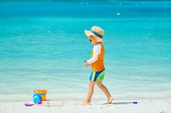 Three year old toddler boy playing with beach toys on beach. Summer family vacation at Maldives.