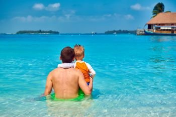 Three year old toddler boy on beach with father. Summer family vacation at Maldives.